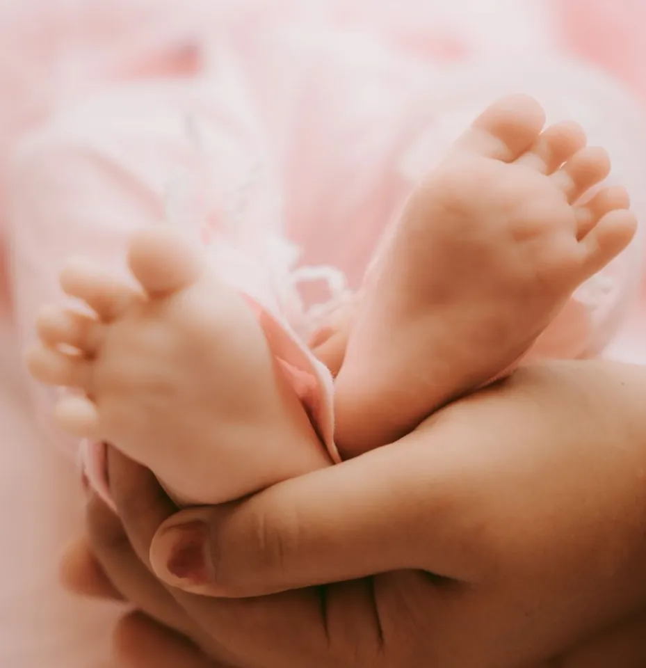 Close-up of a newborn baby’s feet gently held in a parent’s hands